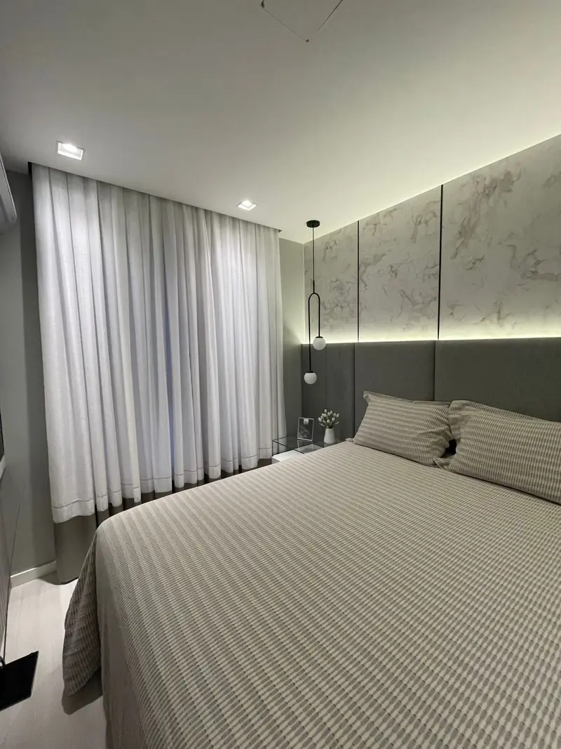 Quarto de casal com cortina branca do teto ao chão e luz indireta